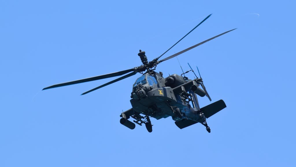 An advanced military helicopter flying high over Miami with a clear blue sky backdrop.