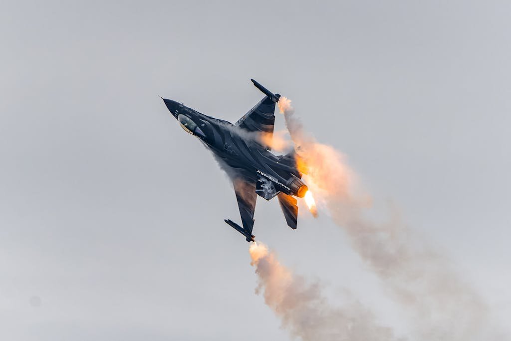 F-16 fighter jet soaring with flames and smoke during an aerial demonstration.